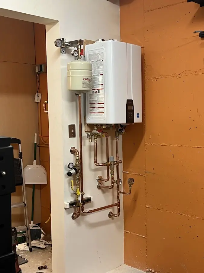 Plumbing technician inspecting water heater connections in Greendale